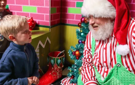 Santa listening to a child at Kringle's Inventionasium experience, an immersive attraction in Seattle for families during Christmas