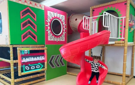 young girl sliding down bright slide at Little Pandas Play Cafe, a new indoor play place near Seattle