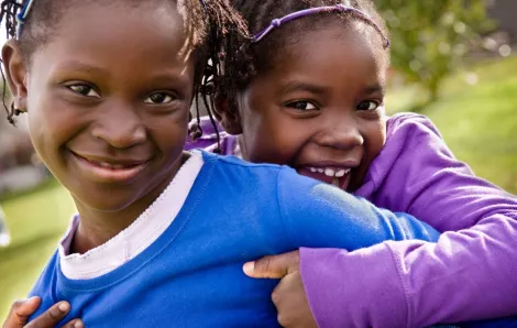 Black History Month events with smiling African American sisters hugging each other. 