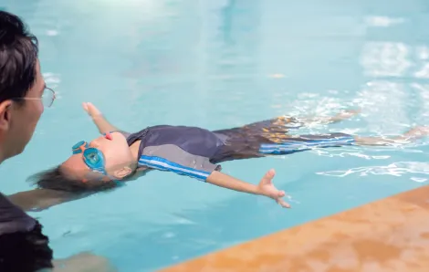 Boy floating in the water on his back in a swimming lesson