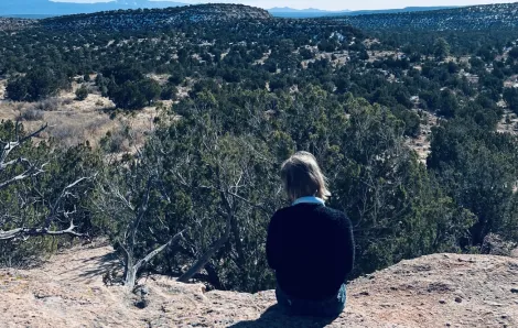 girl sitting and looking out at trees over a ravine. Neurodiverse family travel 