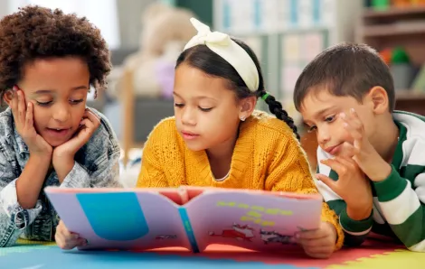 three kids on the floor reading a book together