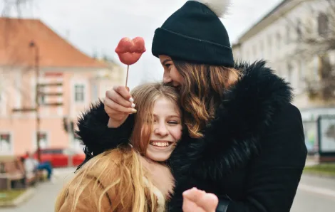 mom and daughter holding suckers shaped like lips smiling and hugging