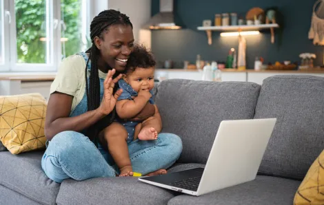 mom holding a baby waving to a computer call finding community online