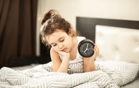 sleepy child holding her alarm clock