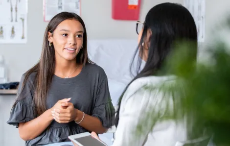 teenage girl talking with doctor at a wellness visit