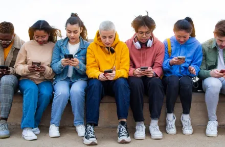 group of teens looking at their phones on social media