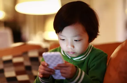 a young child is captivated by a cell phone screen