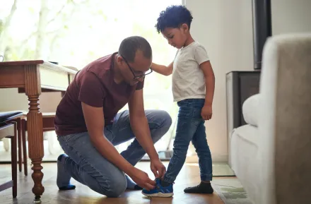 A dad helps his son try on shoes looking for the right size, one that fits