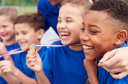 Group of kids holding up gold metals