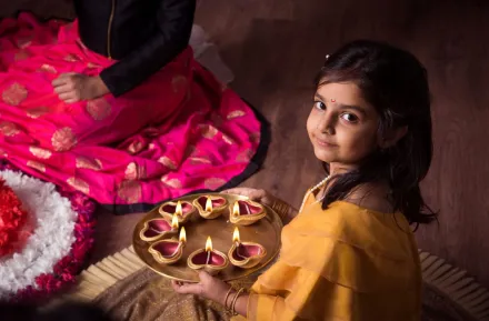 Girl celebrates Diwali Festival of Lights Around Seattle with diya and rangoli.