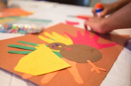 Child's hands making Thanksgiving turkey craft