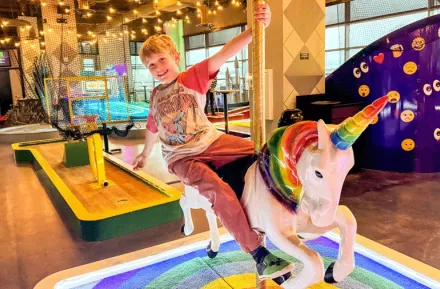 young child at putt putt mini golf course near Seattle on a rainy day, an indoor activity for families