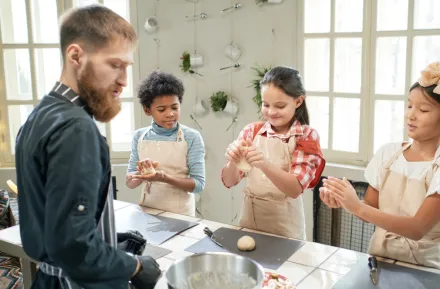 Three kids at a cooking class rolling handfuls of dough, an experience Christmas gift