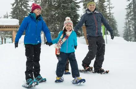 Twp parents and kids snowshoeing in the winter on a family adventure