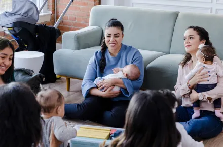 New moms sitting in a living room together connecting as new parents 