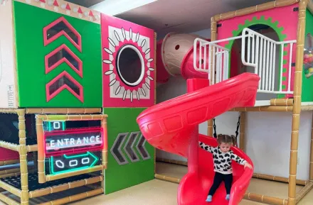 young girl sliding down bright slide at Little Pandas Play Cafe, a new indoor play place near Seattle