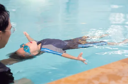 Boy floating in the water on his back in a swimming lesson