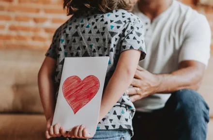 child holding a valentine behind their back for their parent