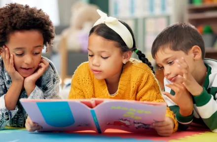 three kids on the floor reading a book together