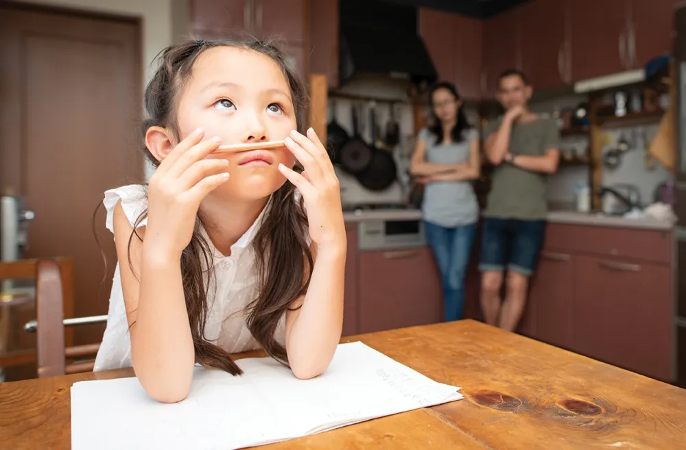 Young girl sitting at a table with homework