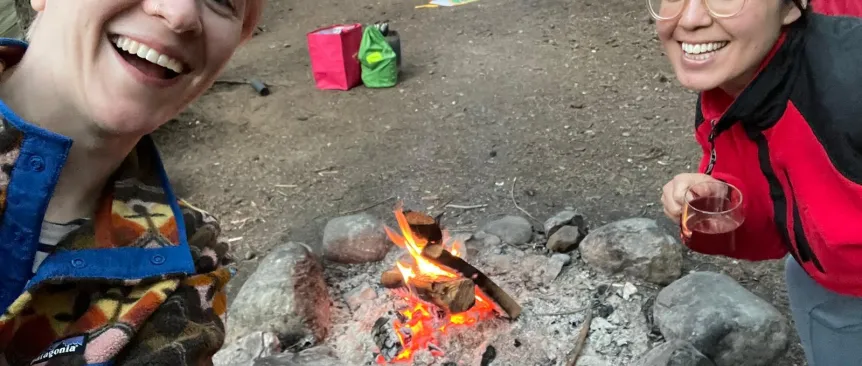 Two mom friends smile for a selfie while camping.