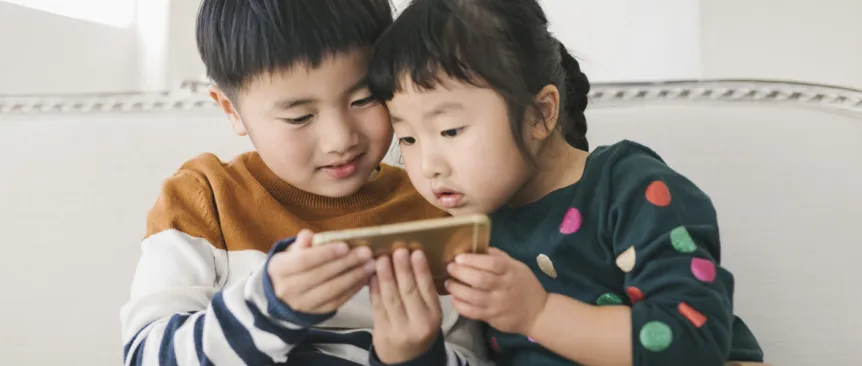 Two young kids looking at a smart phone