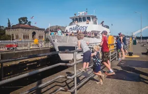 Kids at the Ballard Locks, a top tourist attraction in Seattle, watch an Argosy boat pass through the locks from Lake Washington to Puget Sound