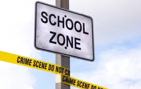 Closeup of School Zone sign with crime scene tape wrapped around it