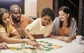 A family sitting at a table playing a board game on a family game night