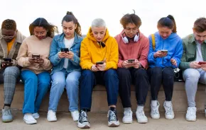 group of teens looking at their phones on social media