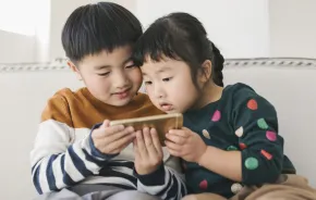 Two young kids looking at a smart phone