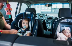 Mom safely buckling kids into their car seats following car seat safety guidelines