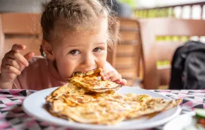 child eating potato and cheese gozleme on wooden table. Traditional stuffed pancakes in Alanya, Turkey. 