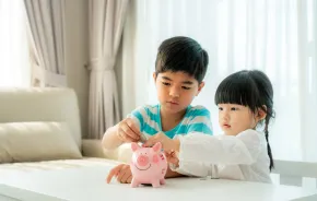 Kids learning to save money putting coins in a piggy bank