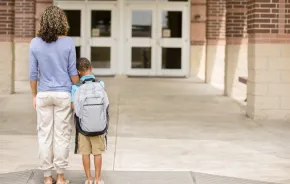 Mom and son standing outside building, child feeling school anxiety