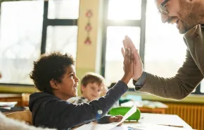 Boy and teacher giving a high five and have a positive student-teacher relationship