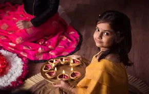 Girl celebrates Diwali Festival of Lights Around Seattle with diya and rangoli.