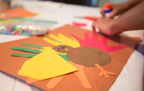 Child's hands making Thanksgiving turkey craft