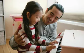 Dad and daughter sitting at a small piano gratitude activities kids