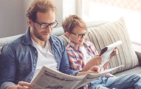 dad and son reading current events in the newspaper