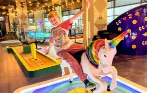 young child at putt putt mini golf course near Seattle on a rainy day, an indoor activity for families