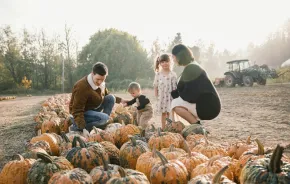 a family with two kids picking pumpkins at a pumpkin patch near Seattle, one of many family-friendly fall activities