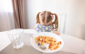 young girl experiencing challenges at a family dinner table 