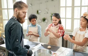 Three kids at a cooking class rolling handfuls of dough, an experience Christmas gift