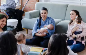 New moms sitting in a living room together connecting as new parents 