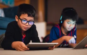 Two boys playing video games on tablets 