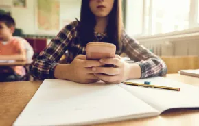 young student looks at her phone in class