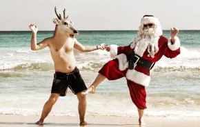 santa dancing with a reindeer on the beach