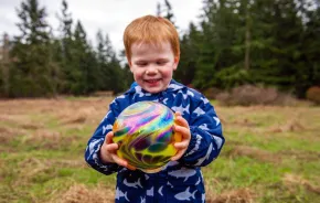 young child holding a glass float found during Northwest Glass Quest, a glass float hunt on Camano Island